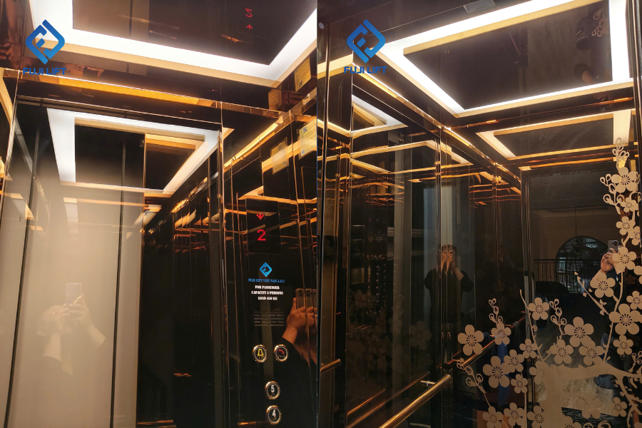 Không gian bên trong cabin lung linh dưới dải đèn LED trần hình khối, nổi bật là bức vách sau Inox gương đồng chạm khắc họa tiết cành hoa sắc nét.